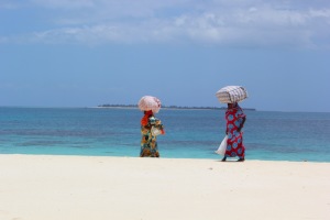 Two women with colorful clothes walking on the sandbank